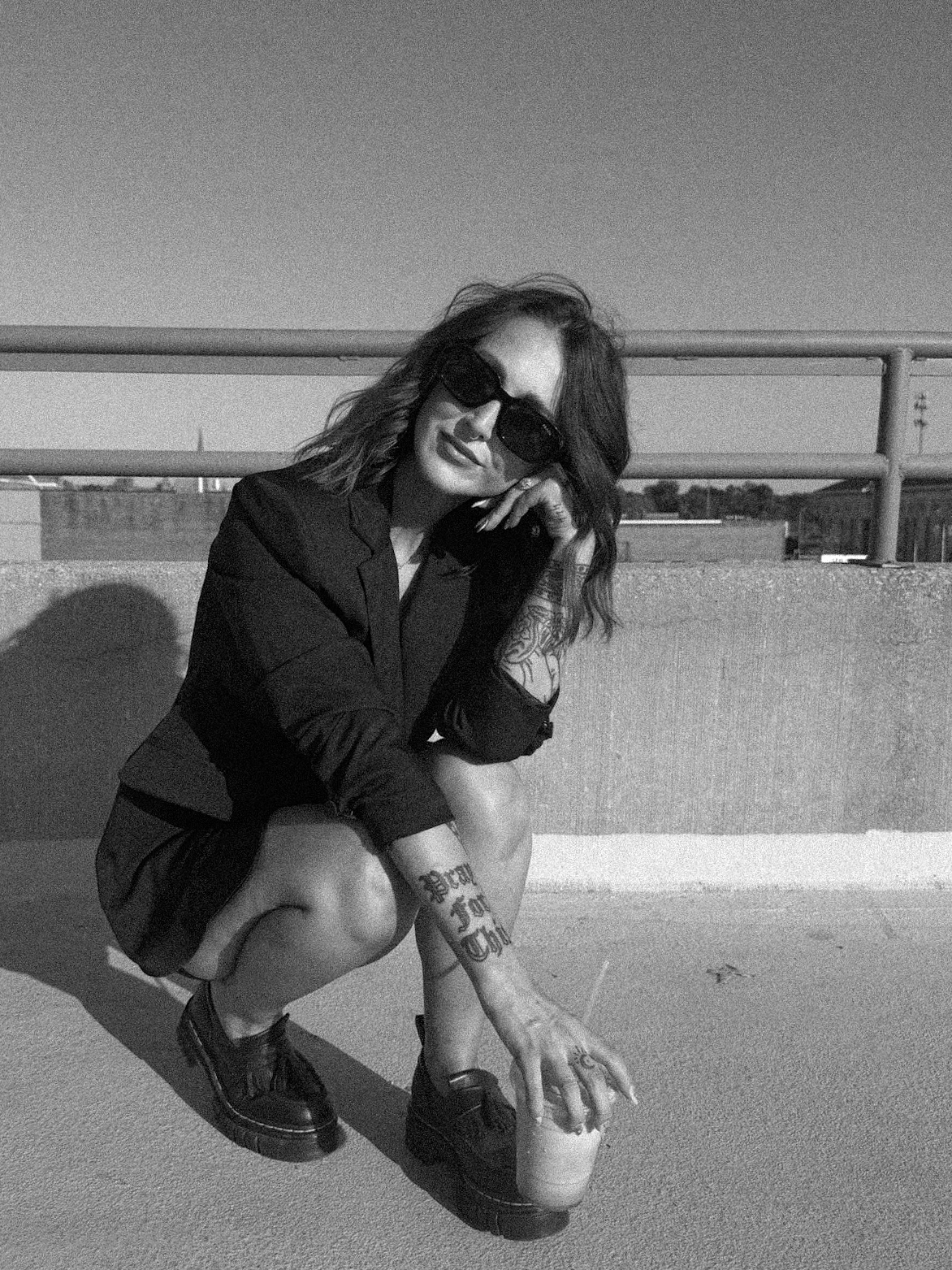 Aubrey Stewart crouching outdoors in sunglasses and a black blazer