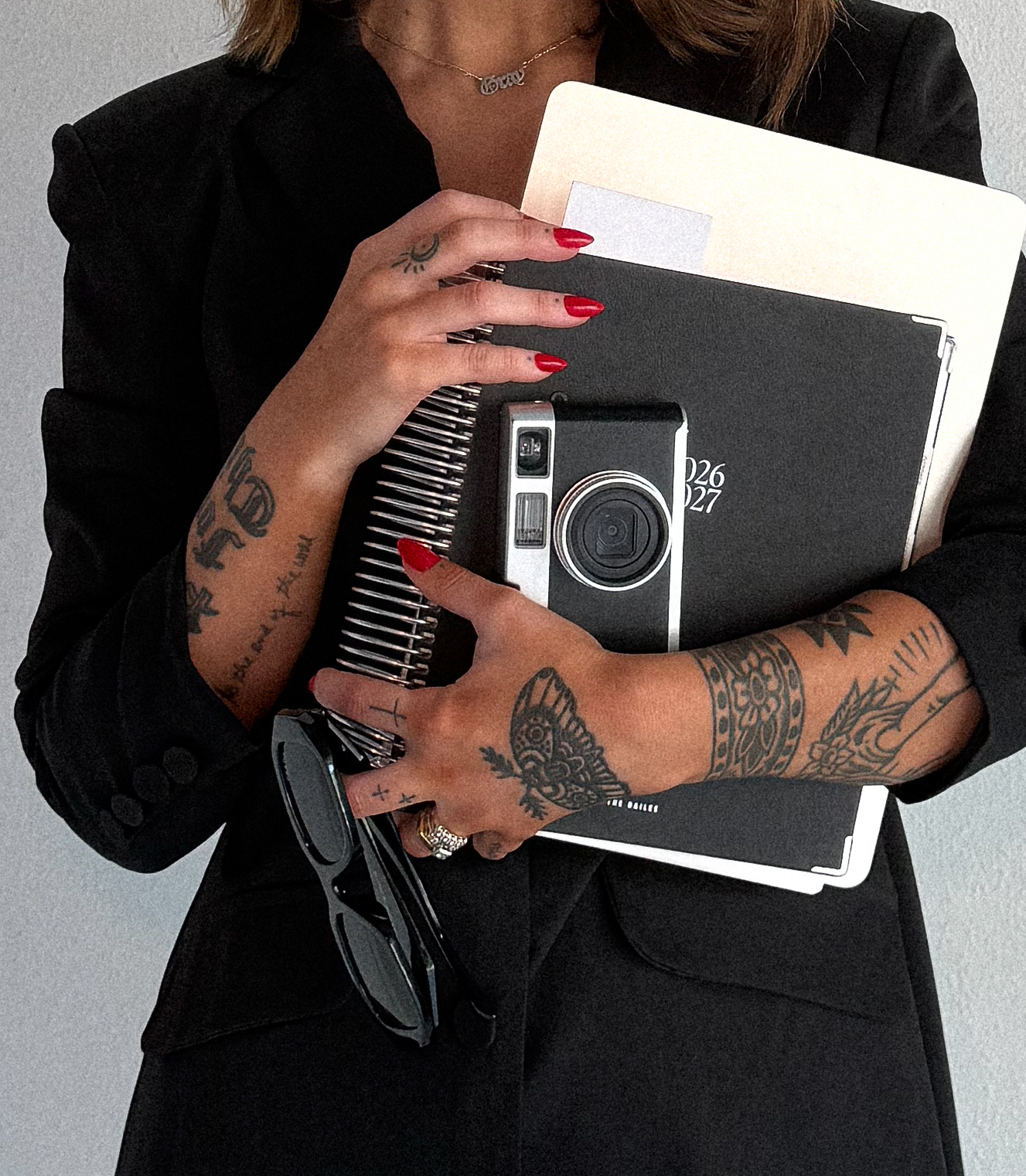 Aubrey Stewart holding a planner, vintage camera, and sunglasses